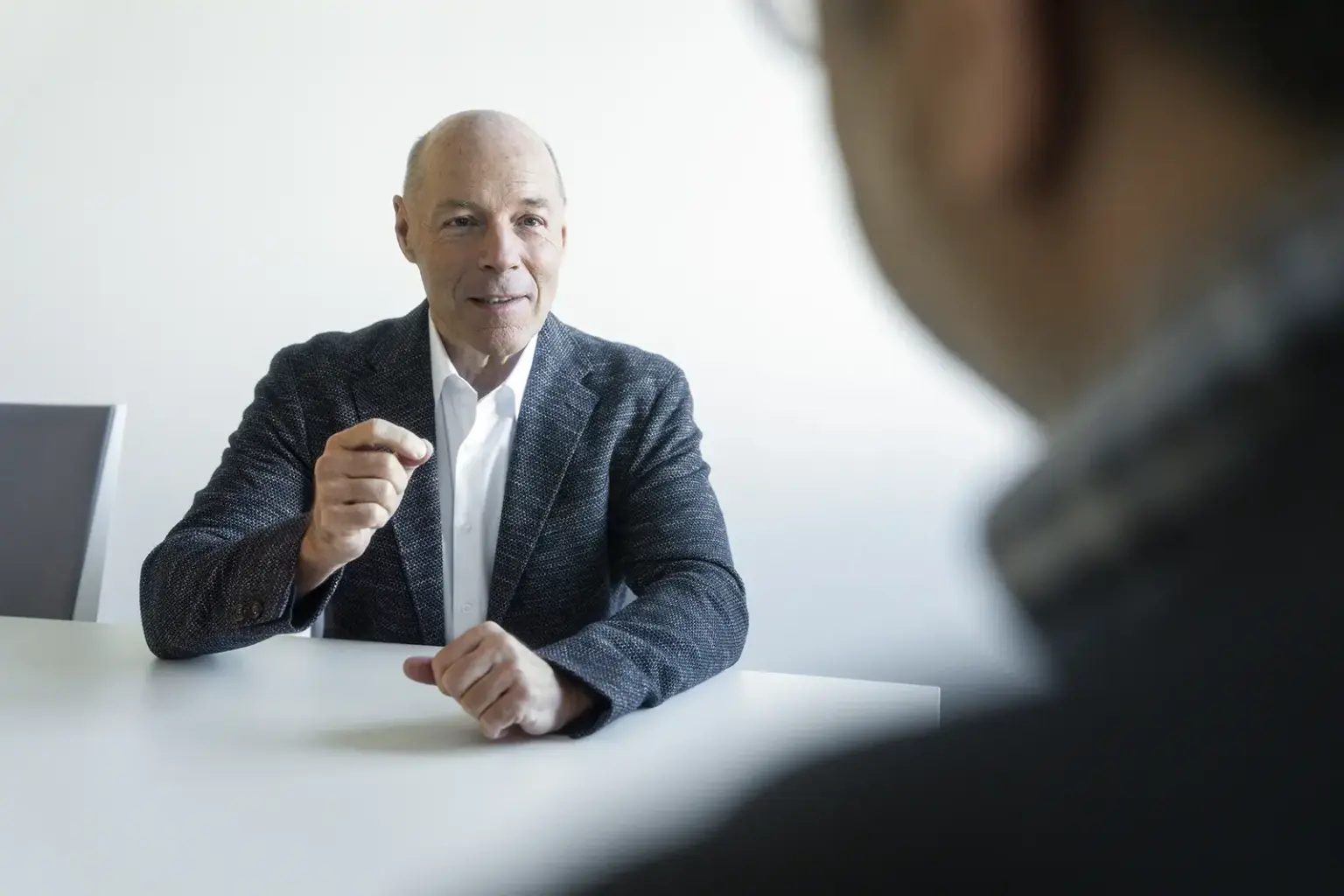 Ein Mann mit schwarzem Sakko und weißem Hemd wird von einem Mann interviewt.