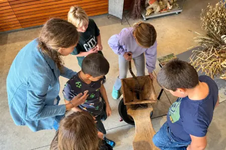 Einige Kinder stehen rund um eine alte Getreidemühle