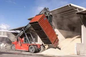 Ein fahrbares Gerät entleert einen Container auf einem Werksgelände