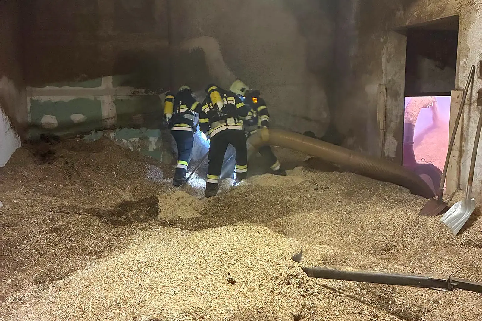 Feuerwehrleute mit schwerem Atemschutz arbeiten in einem verrauchten Hackschnitzellager in einem Kindberger Industriebetrieb.