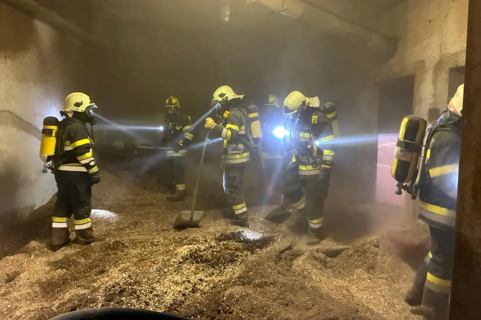 103 Feuerwehrleute bei Brand in Kindberger Industriebetrieb im Einsatz Mehrere Feuerwehrleute mit Atemschutzgeräten suchen und bearbeiten in einem stark verrauchten Hackschnitzellager Glutnester.