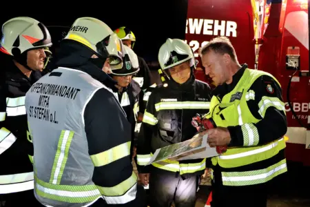 Mehrere Feuerwehrleute beraten sich vor einem Feuerwehrauto