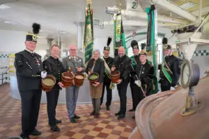 Eine Gruppe von Personen, zum Teil in Uniform, steht mit Eimern in einer Raum mit verschiedenen Geräten