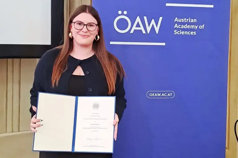 Eine junge Frau präsentiert eine Urkunde