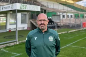 DSV-Leoben-Interimstrainer Alex Bauer steht in grüner Vereinskleidung auf dem Fußballplatz vor der Tribüne des DSV-Stadions in Leoben.