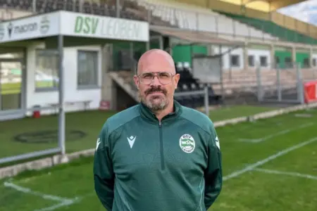 DSV-Leoben-Interimstrainer Alex Bauer steht in grüner Vereinskleidung auf dem Fußballplatz vor der Tribüne des DSV-Stadions in Leoben.