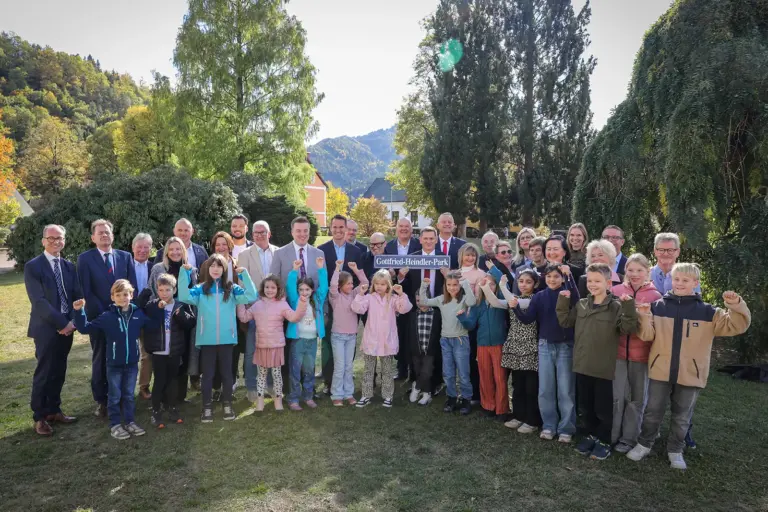 Leoben: Feierliche Eröffnung des Bildungszentrums Fröbelgasse Ein Gruppe von Kindern und Erwachsenen steht in einem Park