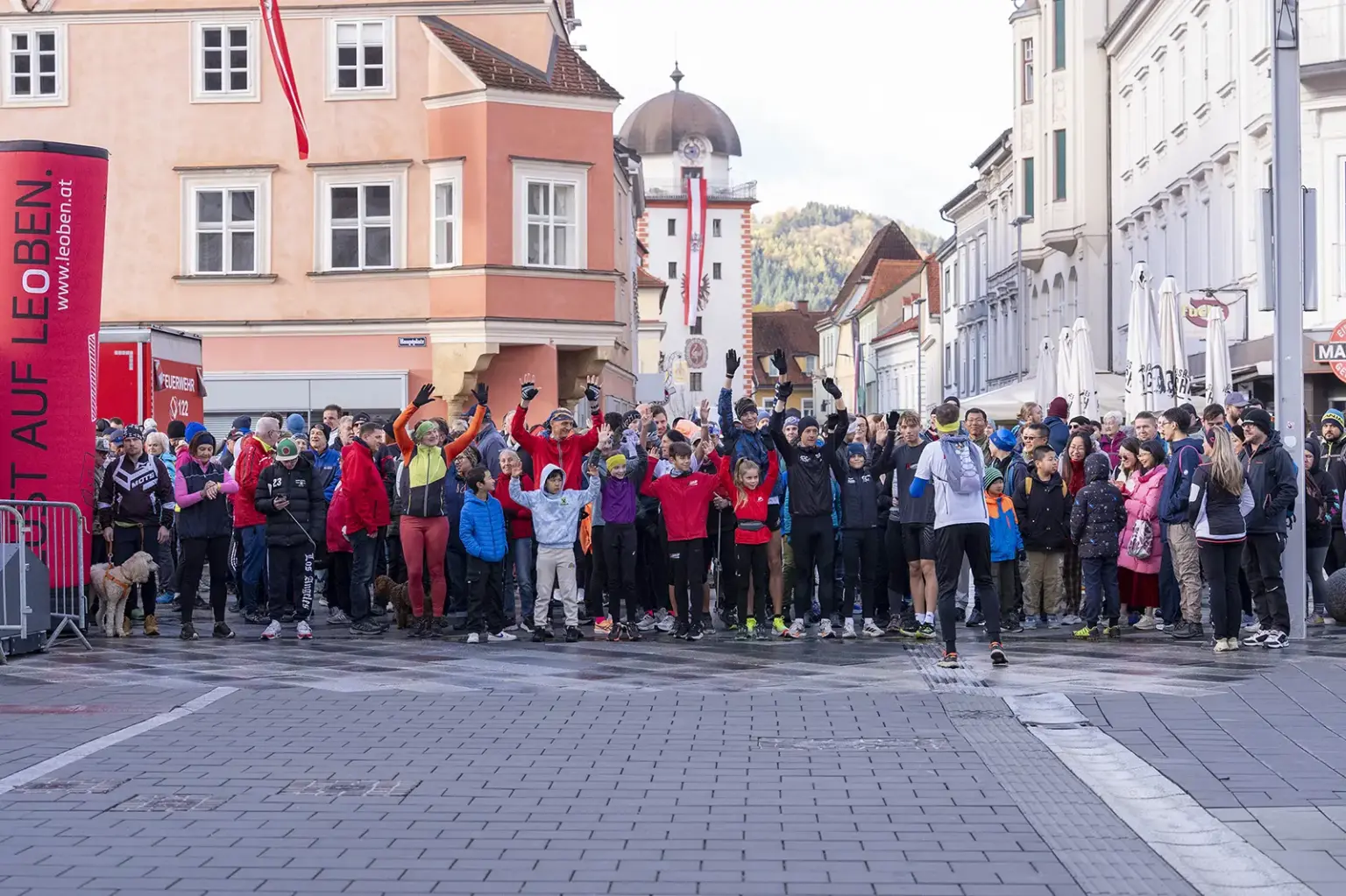 Eine große Gruppe von Menschen in Wander- und Sportkleidung steht auf einem großen Platz