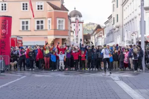 Eine große Gruppe von Menschen in Wander- und Sportkleidung steht auf einem großen Platz