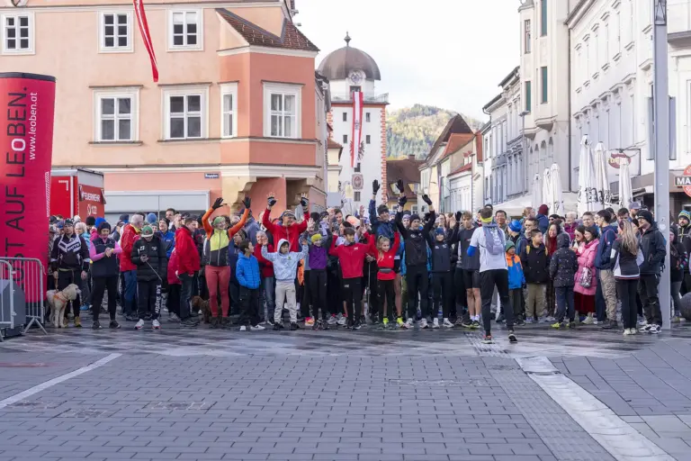 Eine große Gruppe von Menschen in Wander- und Sportkleidung steht auf einem großen Platz