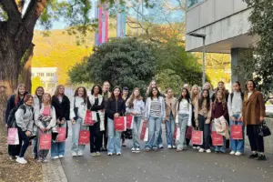 Eine Gruppe von Mädchen steht mit einer Erwachsenen vor einem großen Haus