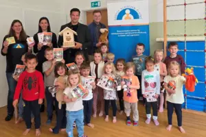 Eine Gruppe von Kindern mit vier Erwachsenen präsentieren verschiedene Broschüren