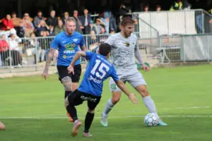 drei Fußballer kämpfen um den Ball.