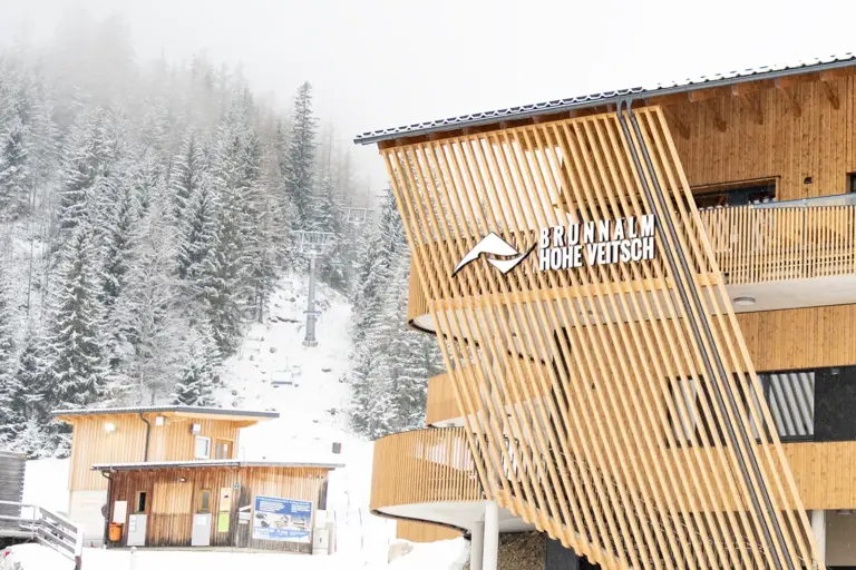 St. Barbara plant Brunnalm-Verkauf um zwei Euro Die Talstation des Skigebiets Brunnalm – Hohe Veitsch in St. Barbara mit ihrer markanten Holzfassade. Im Hintergrund sind der Sessellift und die verschneiten Wälder zu sehen.