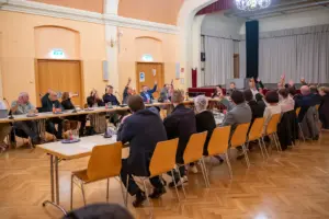 Mit erhobenen Händen stimmen die Mitglieder des Gemeinderats von St. Barbara im Mürztal bei einer Sitzung im Veranstaltungssaal ab.