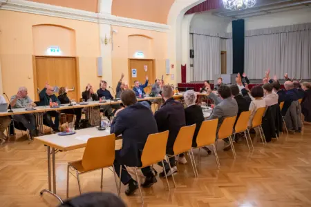 Mit erhobenen Händen stimmen die Mitglieder des Gemeinderats von St. Barbara im Mürztal bei einer Sitzung im Veranstaltungssaal ab.