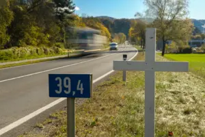 Ein weißes Holzkreuz steht neben einer Straße