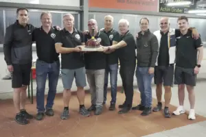 Neun Männer posieren mit einer Trophäe