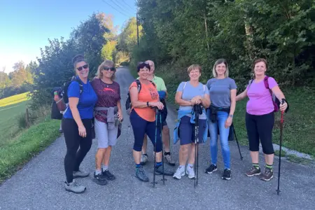Hof-zu-Hof-Wanderung im Lamingtal ist zurück Eine Wandergruppe mit sieben Personen macht bei sonnigem Wetter auf einem von Bäumen gesäumten Weg in Tragöß-St. Katharein Halt. Einige Teilnehmer tragen Rucksäcke und Wanderstöcke.