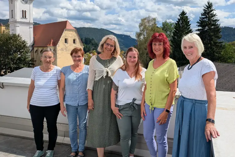 Sechs Frauen stehen an einer Brüstung vor einer Kirche