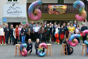 Turnau: Eine Feier rund um die Zahl 63 Eine große Gruppe von Personen steht mit Luftballonen vor einem Haus