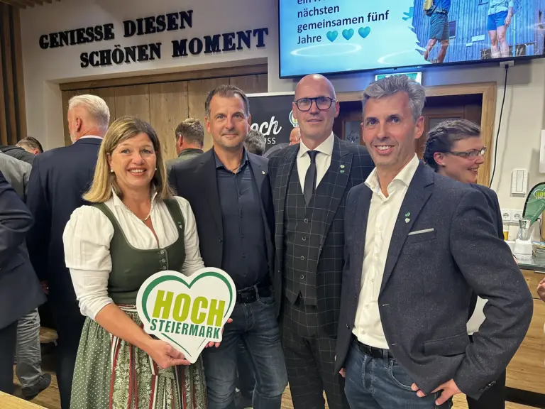 Eine leichte Wahl für die Touristiker Eine Frau mit einem grünen Herz in der Hand zeigt sich mit drei Männern in dunkeln Sakkos.